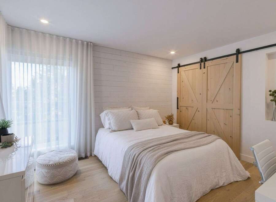 This charming bedroom features a cozy queen-size bed dressed in crisp white linens and a soft, neutral-toned throw blanket.