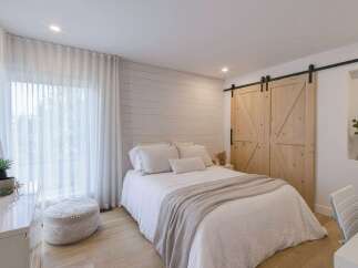 This charming bedroom features a cozy queen-size bed dressed in crisp white linens and a soft, neutral-toned throw blanket.