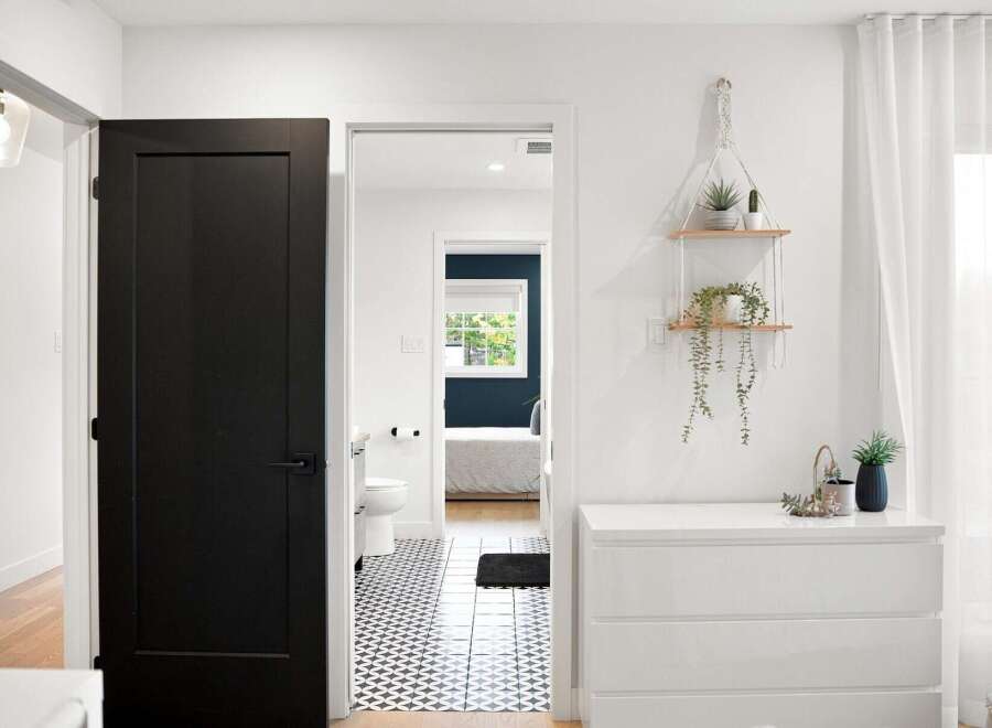 Step into a beautifully designed home featuring a modern black door that opens to a hallway with striking geometric floor tiles.