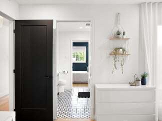 Step into a beautifully designed home featuring a modern black door that opens to a hallway with striking geometric floor tiles.