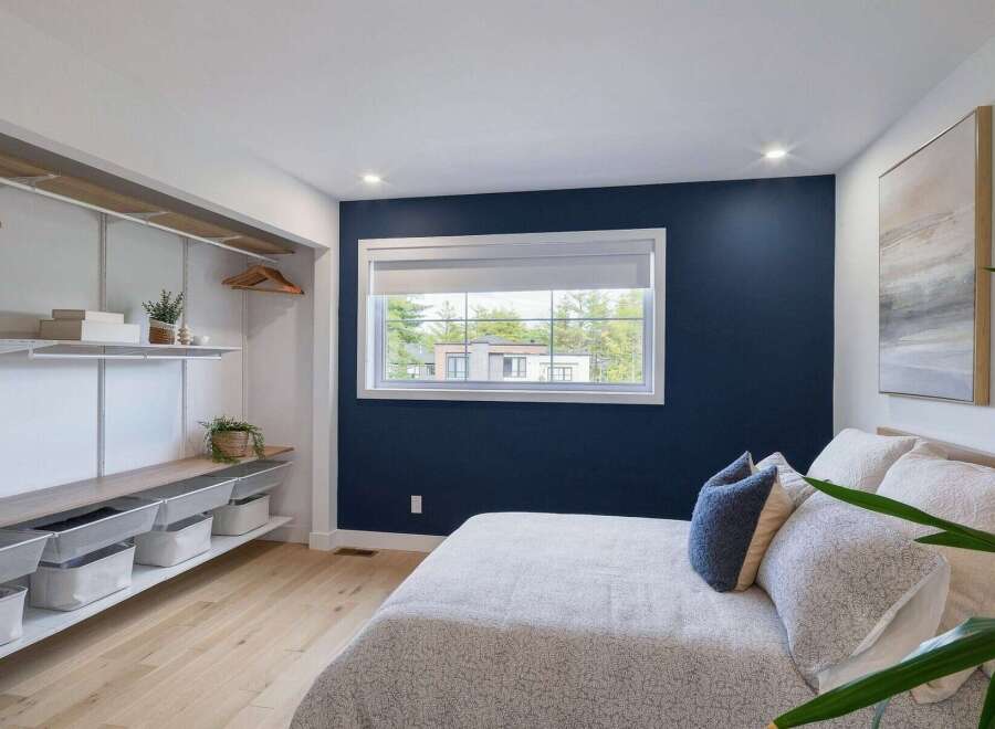 Discover this beautifully designed bedroom featuring a striking navy accent wall that adds a touch of sophistication.