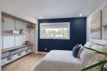 Discover this beautifully designed bedroom featuring a striking navy accent wall that adds a touch of sophistication.