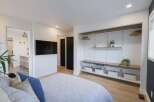 This modern bedroom features a sleek wall-mounted TV and an open-concept closet system with ample shelving and storage baskets.