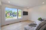Experience modern living in this spacious room featuring a large picture window that offers a stunning view of the contemporary home and its manicured lawn.