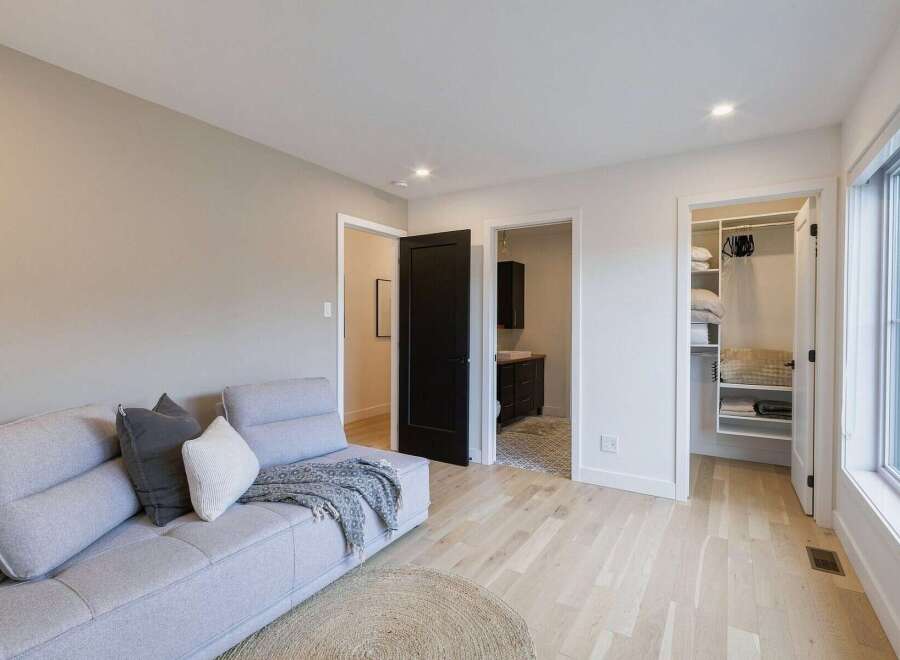 Experience modern living in this beautifully appointed room, featuring a comfortable light gray sectional sofa adorned with accent pillows and a cozy throw.