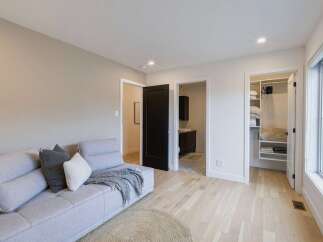 Experience modern living in this beautifully appointed room, featuring a comfortable light gray sectional sofa adorned with accent pillows and a cozy throw.