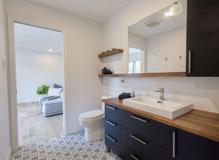 This modern bathroom features a sleek dark vanity with a wooden countertop and a rectangular vessel sink.