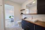 This modern bathroom features a sleek dark vanity with a wooden countertop and a rectangular vessel sink.