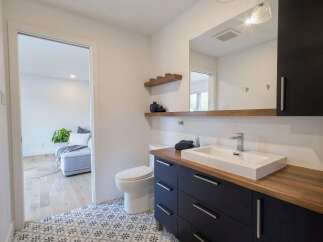 This modern bathroom features a sleek dark vanity with a wooden countertop and a rectangular vessel sink.