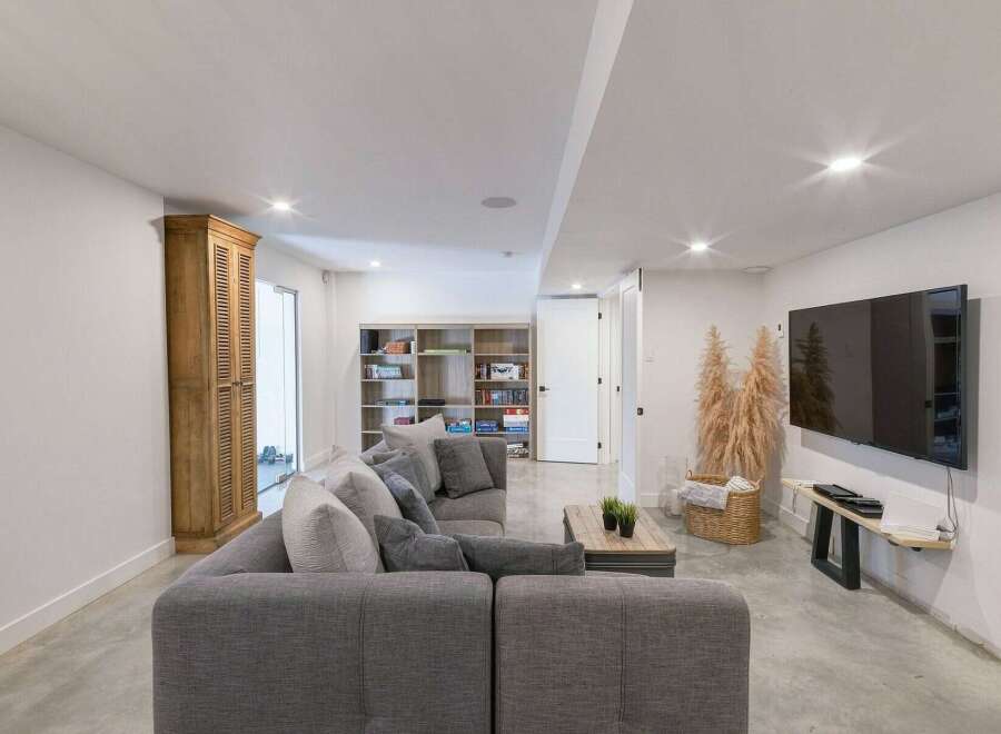 This modern basement living area features a spacious sectional sofa perfect for family gatherings or entertaining guests.