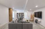 This modern basement living area features a spacious sectional sofa perfect for family gatherings or entertaining guests.