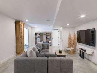 This modern basement living area features a spacious sectional sofa perfect for family gatherings or entertaining guests.