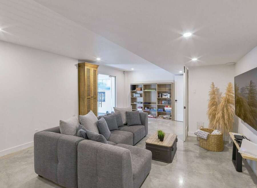 This modern basement living area features a spacious sectional sofa perfect for family gatherings or entertaining guests.
