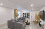 This modern basement living area features a spacious sectional sofa perfect for family gatherings or entertaining guests.