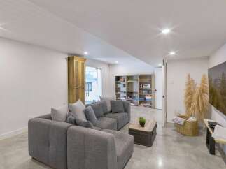 This modern basement living area features a spacious sectional sofa perfect for family gatherings or entertaining guests.