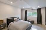 This modern bedroom features a comfortable bed with dark gray and white linens, complemented by a matching nightstand with a wooden accent.