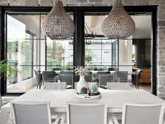 Experience modern luxury in this stunning dining room, featuring a sleek white dining table surrounded by comfortable grey chairs.