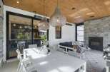 Experience seamless indoor-outdoor living in this beautifully appointed covered patio, featuring a spacious dining area and a cozy lounge space with a stone fireplace.