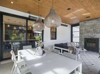 Experience seamless indoor-outdoor living in this beautifully appointed covered patio, featuring a spacious dining area and a cozy lounge space with a stone fireplace.