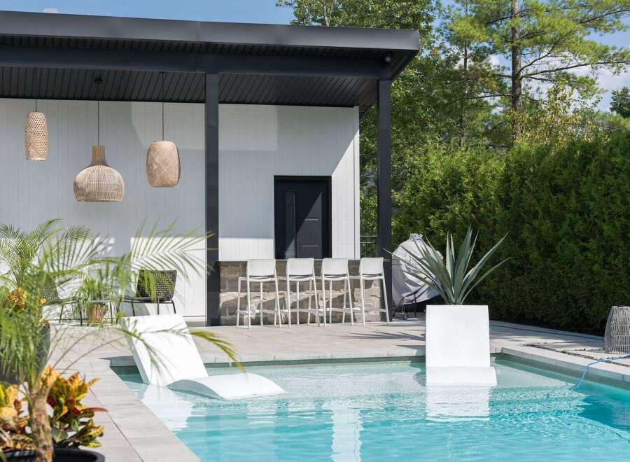 Experience luxurious outdoor living with this modern backyard oasis, featuring a stunning swimming pool and a sleek, covered bar area perfect for entertaining.