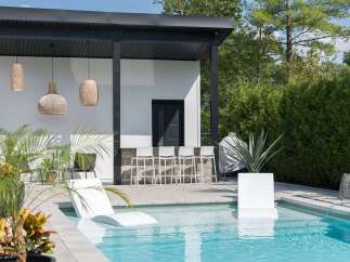 Experience luxurious outdoor living with this modern backyard oasis, featuring a stunning swimming pool and a sleek, covered bar area perfect for entertaining.