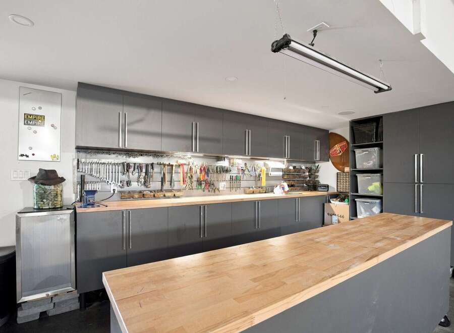 This meticulously organized garage workshop features sleek, dark gray cabinetry providing ample storage for tools and supplies.