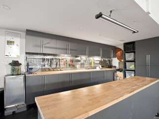 This meticulously organized garage workshop features sleek, dark gray cabinetry providing ample storage for tools and supplies.