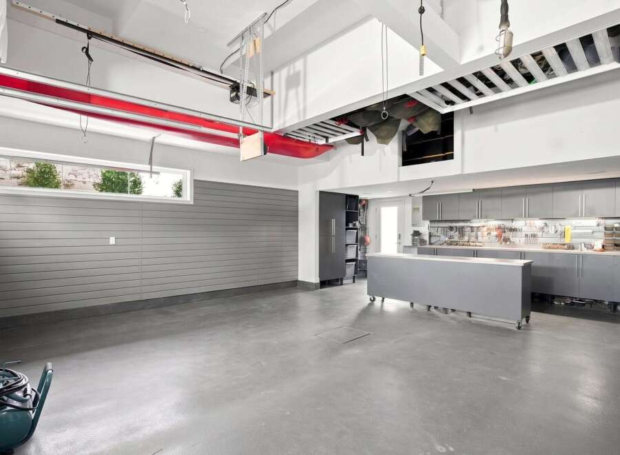 This spacious garage boasts ample storage solutions, including overhead racks and extensive cabinetry, perfect for organizing tools and equipment.