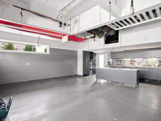 This spacious garage boasts ample storage solutions, including overhead racks and extensive cabinetry, perfect for organizing tools and equipment.