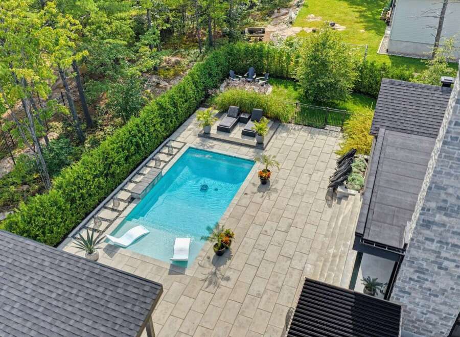 Experience luxury outdoor living with this stunning backyard oasis, featuring a pristine swimming pool surrounded by a spacious stone patio.