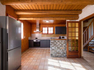 Experience rustic charm in this cozy kitchen featuring warm wood paneling and exposed beams.
