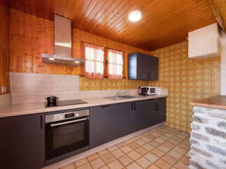 Discover this charming kitchen featuring warm wood paneling and a modern stainless steel range hood.