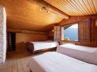 Experience cozy mountain living in this charming attic bedroom, featuring warm wooden paneling and a vaulted ceiling.
