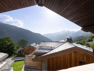 Experience breathtaking mountain views from this stunning property, featuring modern chalets with traditional wooden architecture and slate roofs.