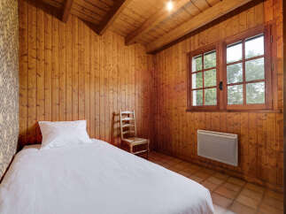 Experience cozy living in this charming bedroom featuring warm, wood-paneled walls and a vaulted ceiling with exposed beams.