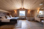 Experience ultimate relaxation in this luxurious mountain retreat, featuring a spacious bedroom with a cozy king-size bed and plush fur pillows.