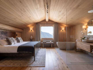 Experience ultimate relaxation in this luxurious mountain retreat, featuring a spacious bedroom with a cozy king-size bed and plush fur pillows.