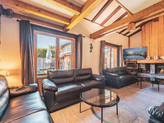 Experience cozy living in this charming mountain retreat, featuring a rustic stone fireplace and exposed wooden beams that add warmth and character.