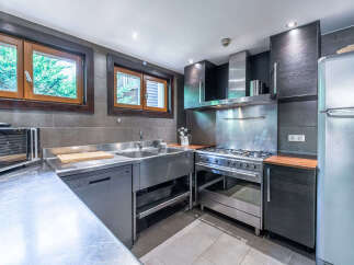 This spacious kitchen features a large stainless steel double sink, a professional-grade gas range with a powerful exhaust hood, and a modern LG microwave.