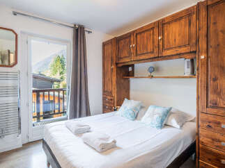 Experience mountain living in this charming bedroom featuring a comfortable bed adorned with decorative pillows and crisp white linens.