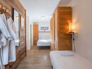 Experience alpine charm in this cozy bedroom featuring two comfortable beds and ample wooden storage.