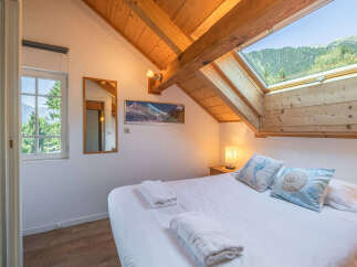 Experience breathtaking mountain views from this charming attic bedroom, featuring a large skylight that floods the space with natural light.
