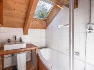 Experience rustic charm in this bathroom featuring a wooden vanity with a vessel sink and a relaxing bathtub.
