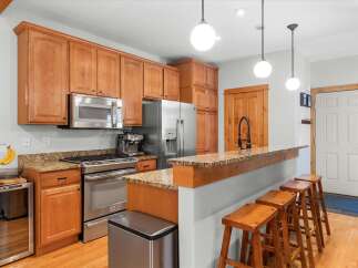 This spacious kitchen boasts beautiful natural wood cabinetry and granite countertops, offering a warm and inviting atmosphere.