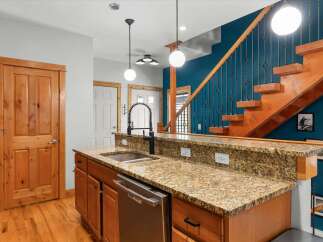 Discover this stunning kitchen featuring a granite countertop with a deep sink and a modern faucet, complemented by warm wooden cabinetry and a stainless steel dishwasher.