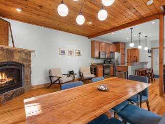 Experience cozy living with this inviting dining and kitchen area, featuring a stunning stone fireplace and a beautiful live-edge dining table.