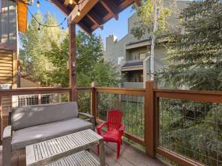 Enjoy outdoor living on this charming deck, complete with comfortable seating and a rustic wooden coffee table.