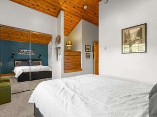 Experience rustic charm in this inviting bedroom featuring a vaulted wood-paneled ceiling and a spacious mirrored closet.