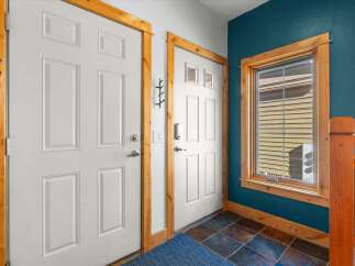 Step into this inviting entryway featuring two white paneled doors, one with a modern smart lock, and a charming branch-like coat rack.