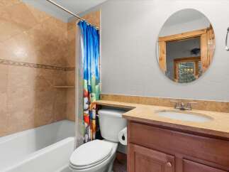 This bathroom features a bathtub with a tiled shower surround and a colorful shower curtain.
